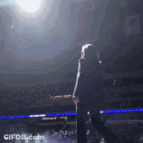 Woman On Stage In Front Of Crowd With Tl Sign GIF