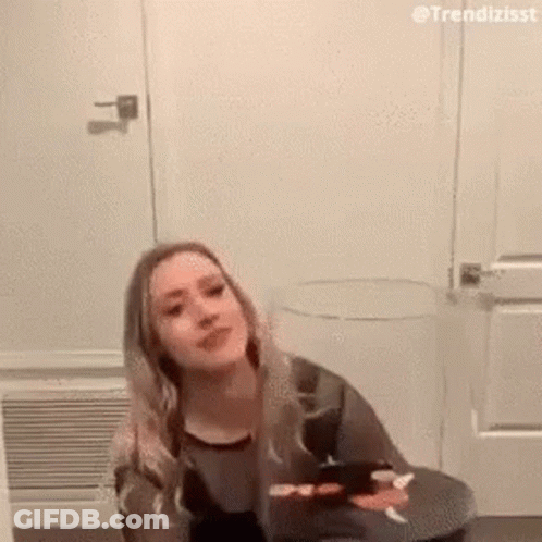 Woman On Stool By Door Looking At Camera GIF