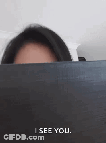 Woman Peeking Behind Laptop Saying I See You GIF