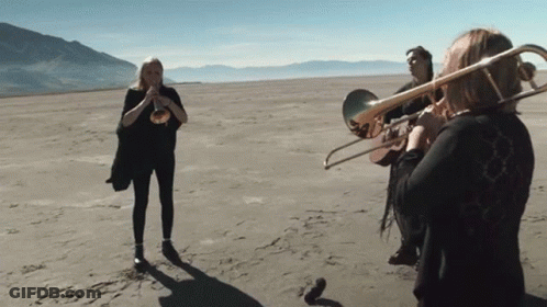 Woman Playing Trombone In Desert GIF