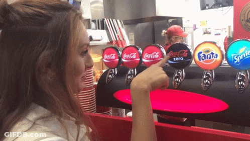 Woman Pointing At Coca Cola Sprite And Fanta Dispenser GIF
