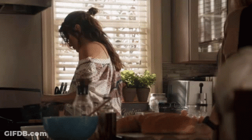 Woman Preparing Food In Kitchen With Cucina Sign GIF