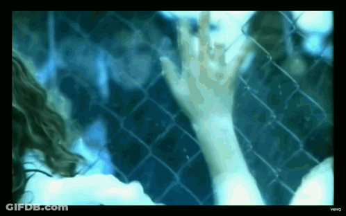 Woman Reaching Toward Chain Link Fence GIF