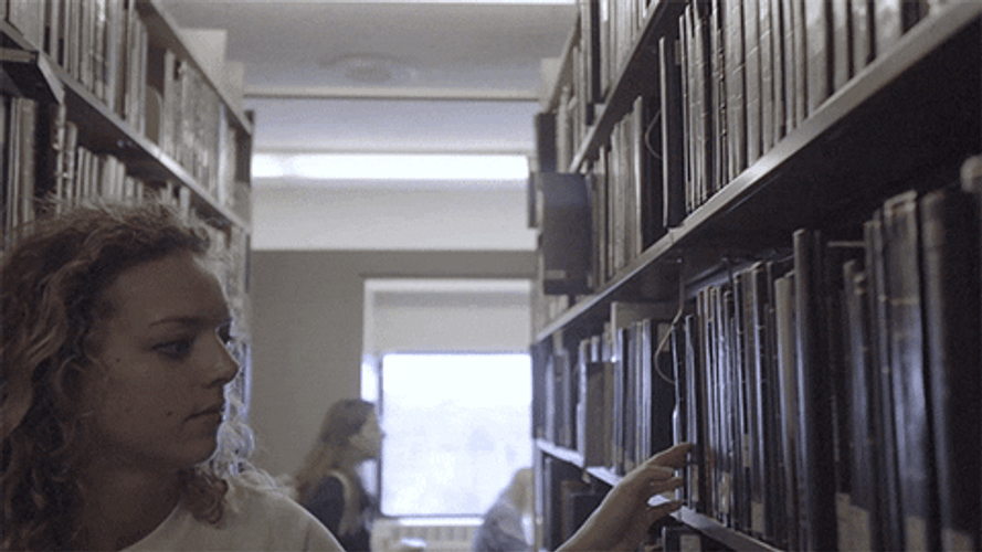 Woman Reading Book Inside Library GIF