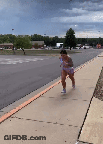 Woman Running Down Sidewalk With Stop Sign GIF
