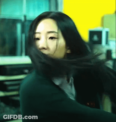 Woman's Hair Blowing In Wind Against Yellow Wall GIF