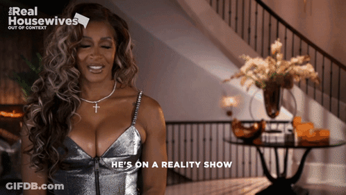 Woman Saying He's On Reality Show In Silver Dress GIF