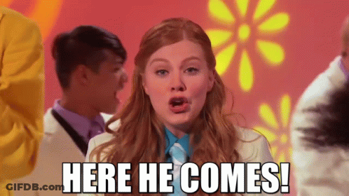 Woman Saying Here He Comes With Flowers GIF