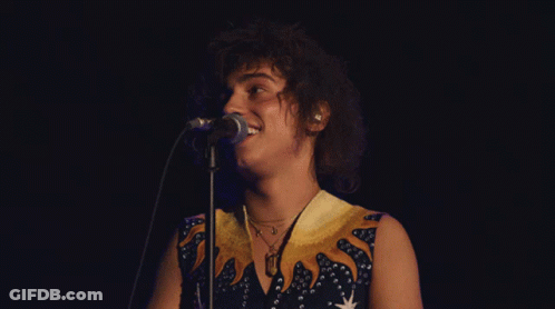 Woman Singing Into Microphone In Blue And Yellow Dress GIF