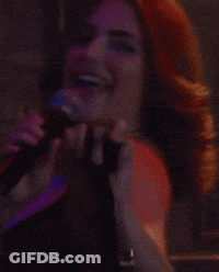 Woman Singing Into Microphone In Front Of Boston Sign GIF