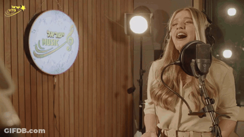 Woman Singing Into Microphone In Front Of Music Sign GIF
