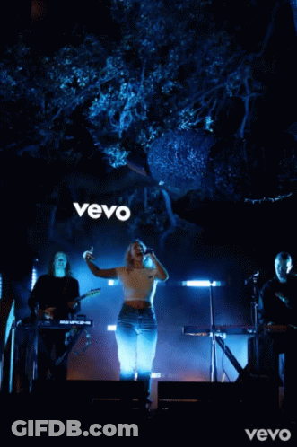 Woman Singing Into Microphone In Front Of Vevo Sign GIF