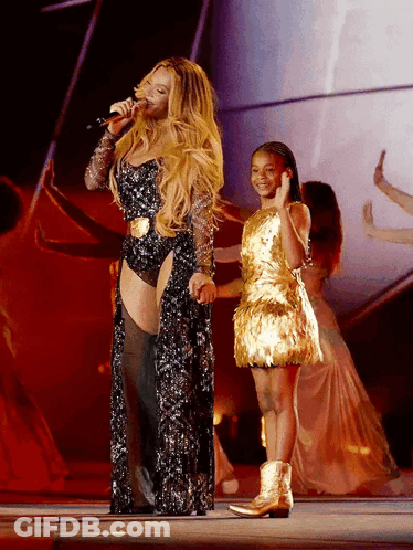 Woman Singing Into Microphone Next To Girl In Gold Dress GIF
