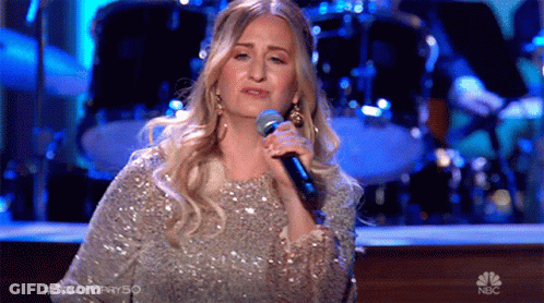 Woman Singing Into Microphone On Stage With NBC Logo GIF
