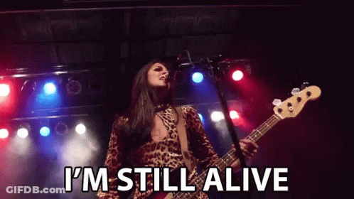 Woman Singing Into Microphone Playing Guitar Saying I'm Still Alive GIF