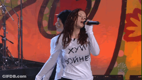 Woman Singing Into Microphone Wearing Shirt Saying ХУЙ GIF