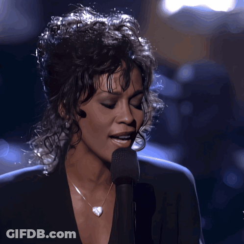 Woman Singing Into Microphone With Heart Necklace GIF