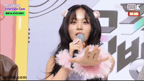 Woman Singing Into Microphone With Pink Necklace GIF