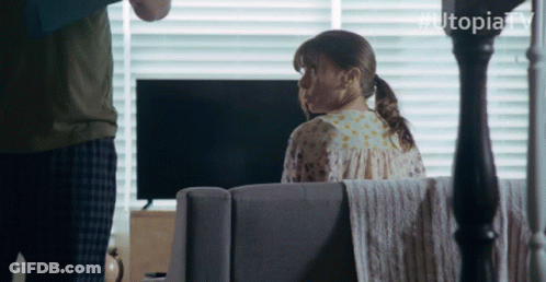 Woman Sits On Couch In Front Of TV With Hashtag Utopiatv GIF