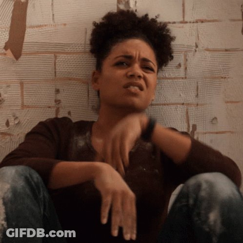 Woman Sitting Against Brick Wall GIF