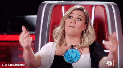 Woman Sitting Arms Outstretched In Front Of NBC Sign GIF