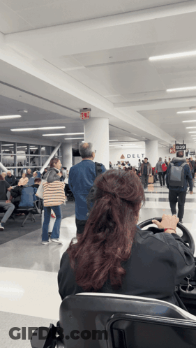 Woman Sitting At Airport With Delta Sign GIF