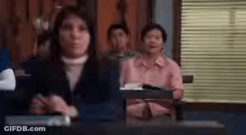 Woman Sitting At Desk In Front Of Group GIF