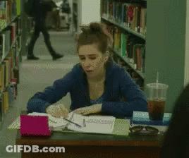 Woman Sitting At Desk In Library With Coffee GIF