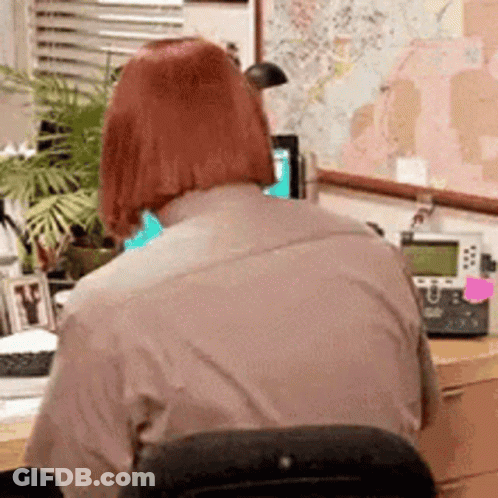 Woman Sitting At Desk With Computer And Phone GIF