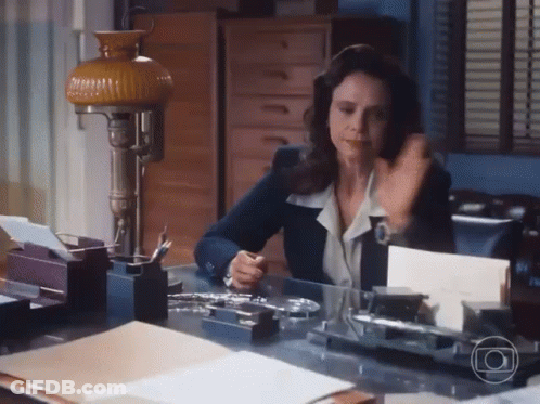 Woman Sitting At Desk With Lamp And Papers GIF