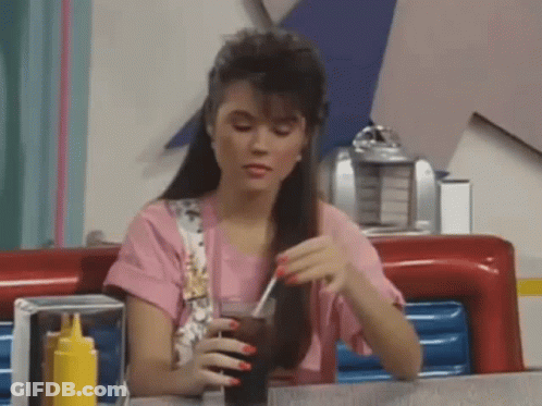 Woman Sitting At Diner Table Holding Soda GIF