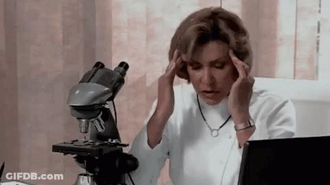 Woman Sitting At Microscope Holding Head GIF