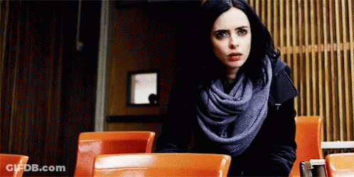 Woman Sitting At Restaurant Table Wearing Scarf And Black Jacket GIF