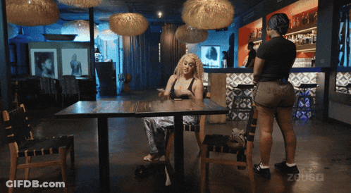 Woman Sitting At Restaurant Table With Woman Behind GIF