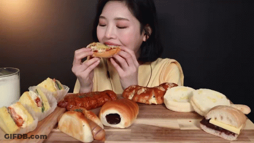 Woman Sitting At Table Eating Bread GIF