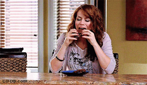 Woman Sitting At Table Eating Brownie GIF