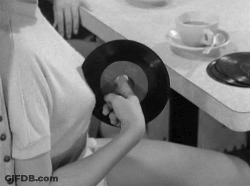 Woman Sitting At Table Holding Record GIF