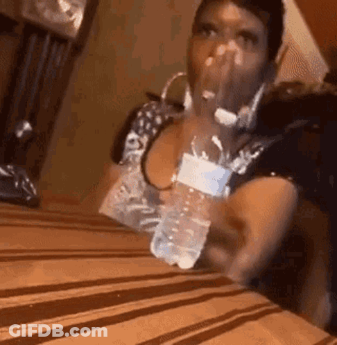 Woman Sitting At Table Holding Water Bottle GIF