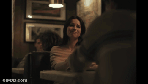 Woman Sitting At Table In Dark Room GIF