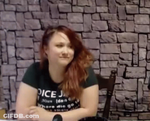 Woman Sitting At Table In Front Of Brick Wall GIF