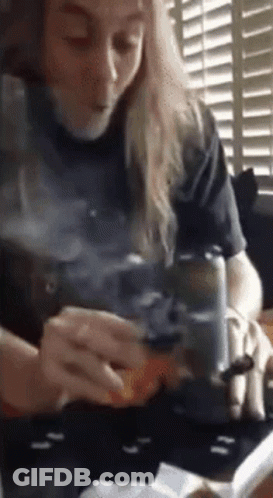 Woman Sitting At Table Smoking Cigarette While Reading Book GIF