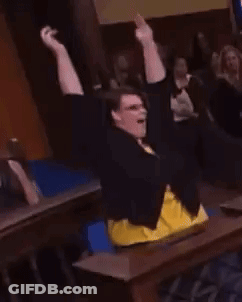 Woman Sitting At Table With Arms In Air GIF