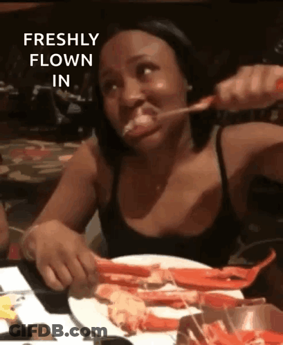 Woman Sitting At Table With Crab Legs And Spoon In Mouth GIF