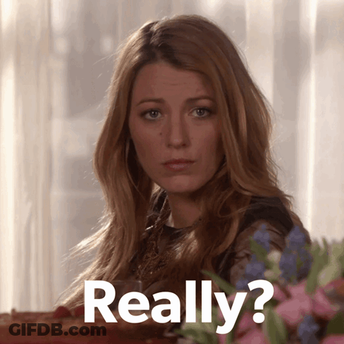 Woman Sitting At Table With Flowers Saying Really GIF