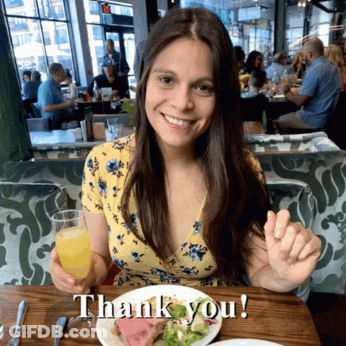 Woman Sitting At Table With Food And Orange Juice Saying Thank You GIF