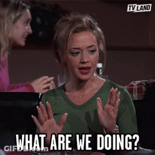 Woman Sitting At Table With Hands Up What Are We Doing GIF