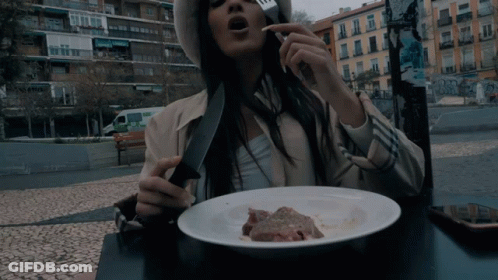Woman Sitting At Table With Plate Of Food And Knife GIF