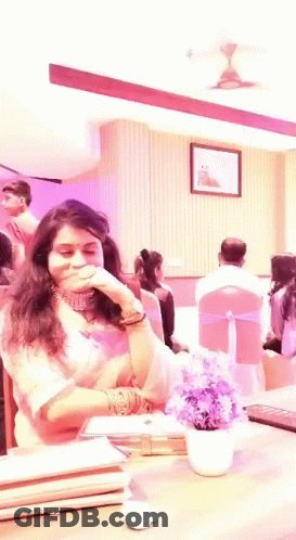 Woman Sitting At Table With Purple Flowers GIF