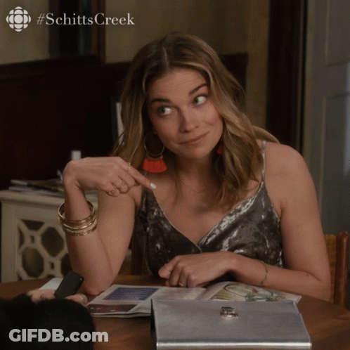 Woman Sitting At Table With Schitts Creek Logo GIF