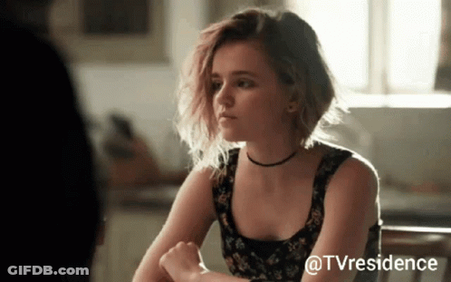 Woman Sitting At Table With TV Residence Watermark GIF